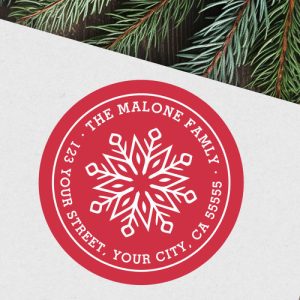 Personalized red and white round snowflake return address label featuring a bold snowflake design at the center with custom family name and address text around the border. Perfect for Christmas cards and holiday mail.