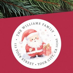Personalized round return address label with watercolor Santa holding a gift. Circular design with customizable family name and address around the border.