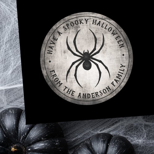 Round Halloween sticker with black spider silhouette on distressed gray background, customizable text reading “Have a Spooky Halloween” and “From the [Your Family Name].” Perfect for party favors, invitations, and treat bags.